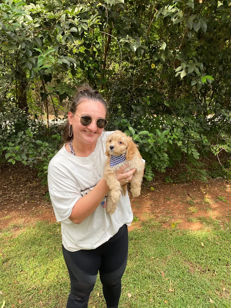 A woman holding a Charlotte Dog Club puppy outdoors
